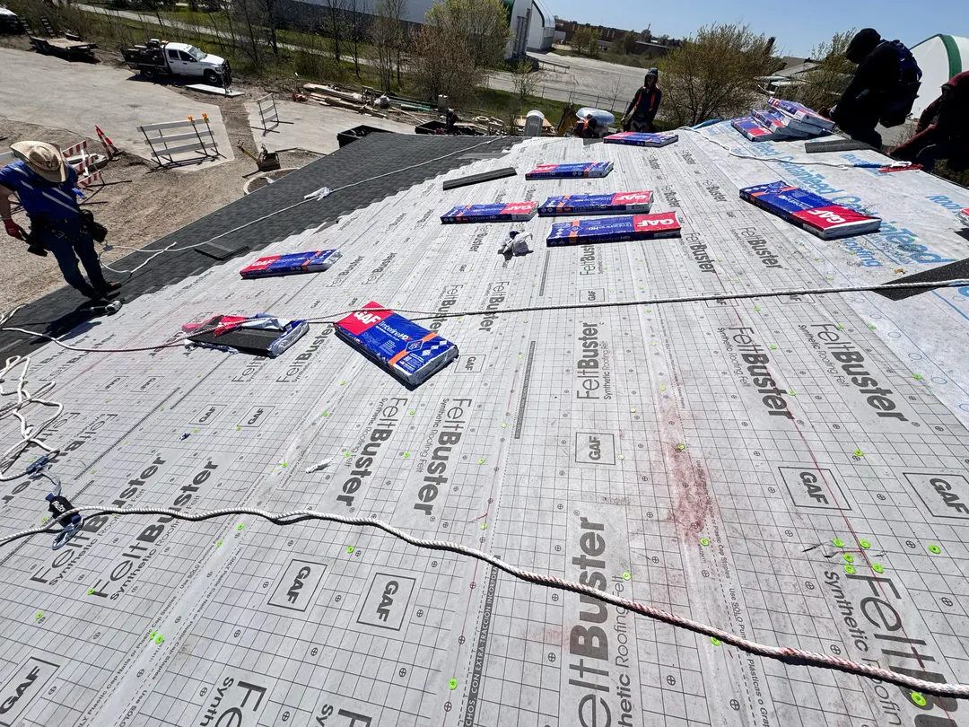 A Falcon crew installing synthetic underlayment, one of the details cheap bids skip.